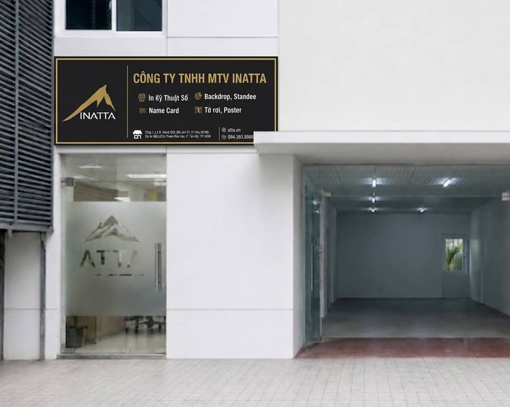 Ảnh chụp mặt tiền cửa hàng in nhanh INATTA tại tầng 1 khu thương mại dự án Belleza Quận 7 TP.HCM vào buổi sáng, biển hiệu chữ trắng trên nền xanh navy đậm kèm điểm nhấn cam, mặt kính lớn nhìn thấy máy in bên trong, kệ trưng bày mẫu tờ rơi và name card đặt trước cửa, vài xe máy đậu trên vỉa hè, ánh nắng nhẹ đầu ngày, chụp ngang tầm mắt góc chéo 30 độ, ảnh thương mại chân thực, tỉ lệ 16:9